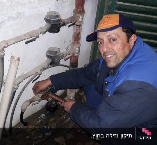 אדם מתקן צינורות עם מפתח צינורות